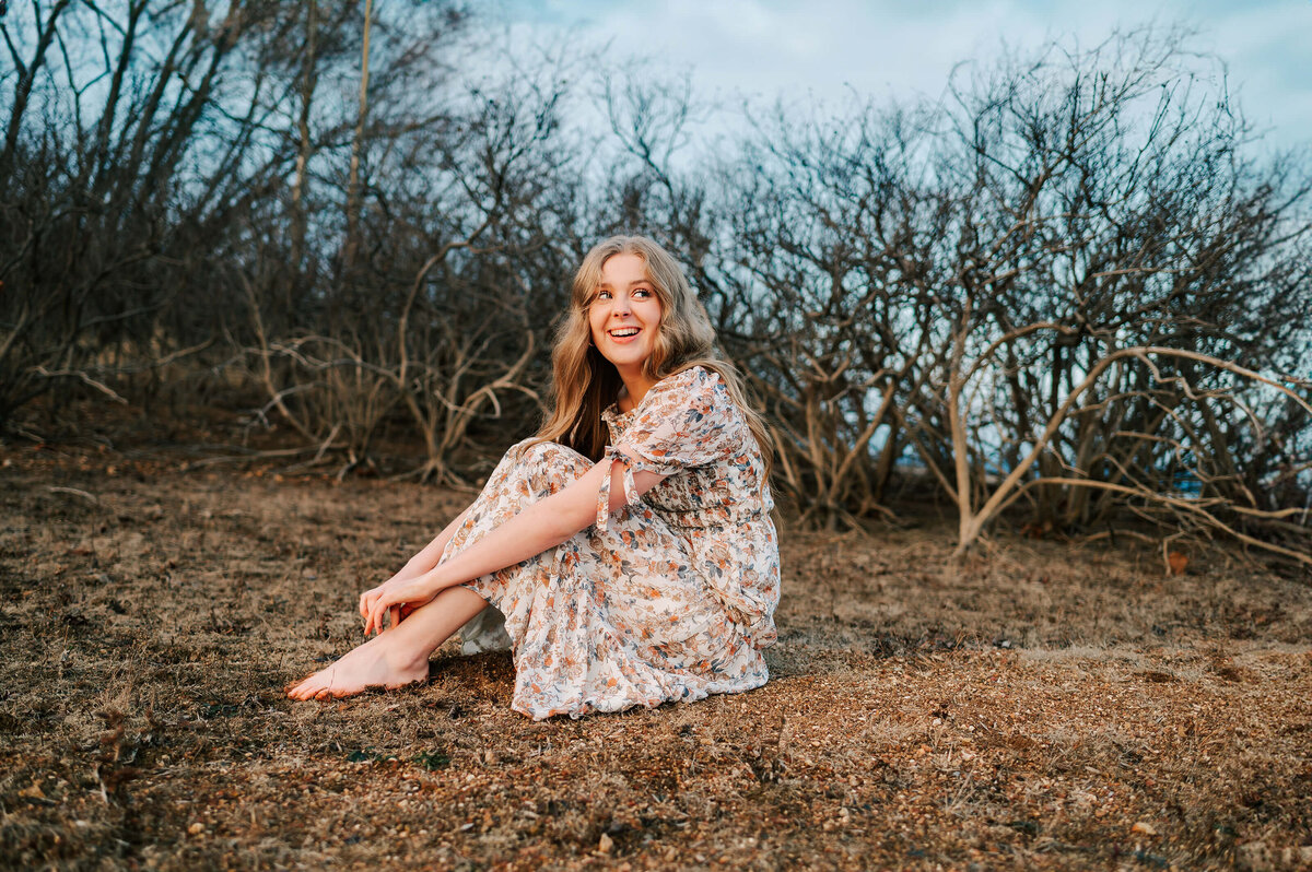 senior girl sitting and laughing outdoors captured by Branson Mo senior photographer Jessica Kennedy of The XO Photography