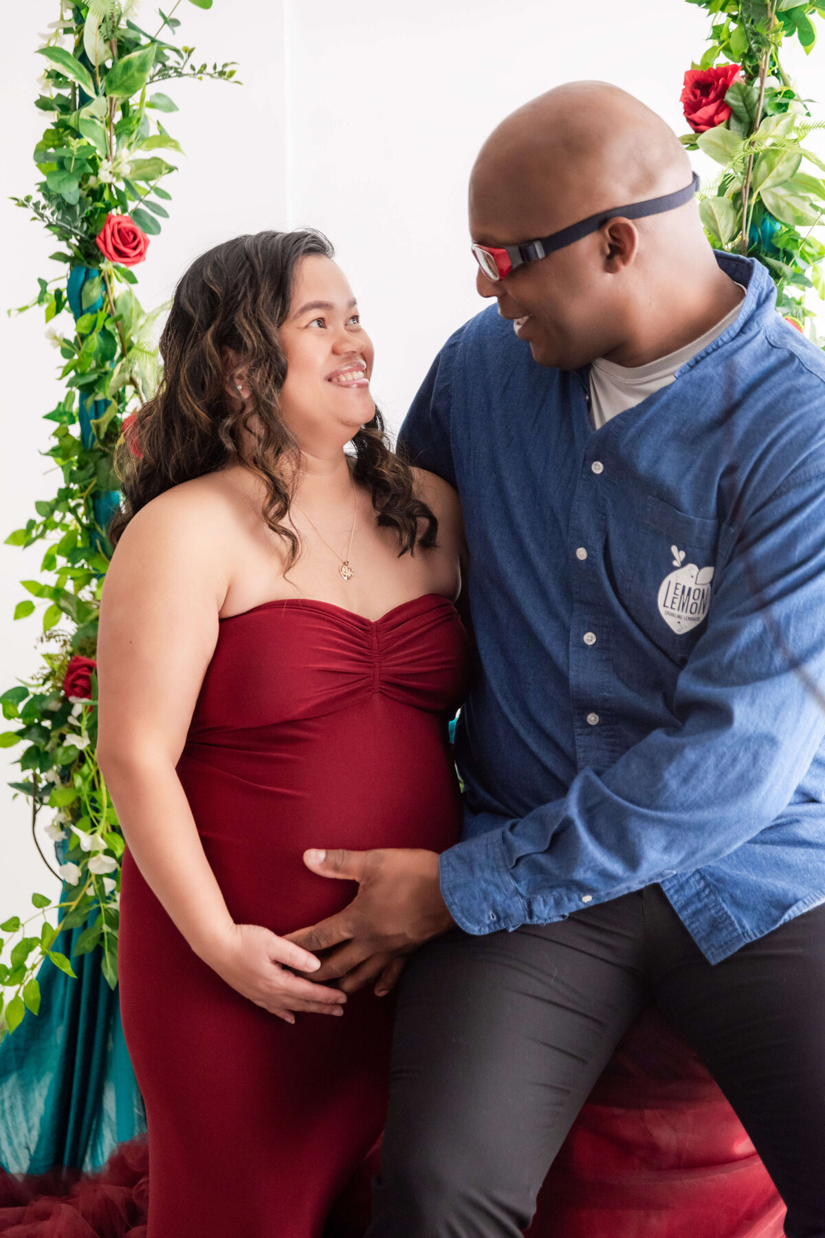 A happy couple, with the woman pregnant, smiles together for the camera, capturing a joyful moment.