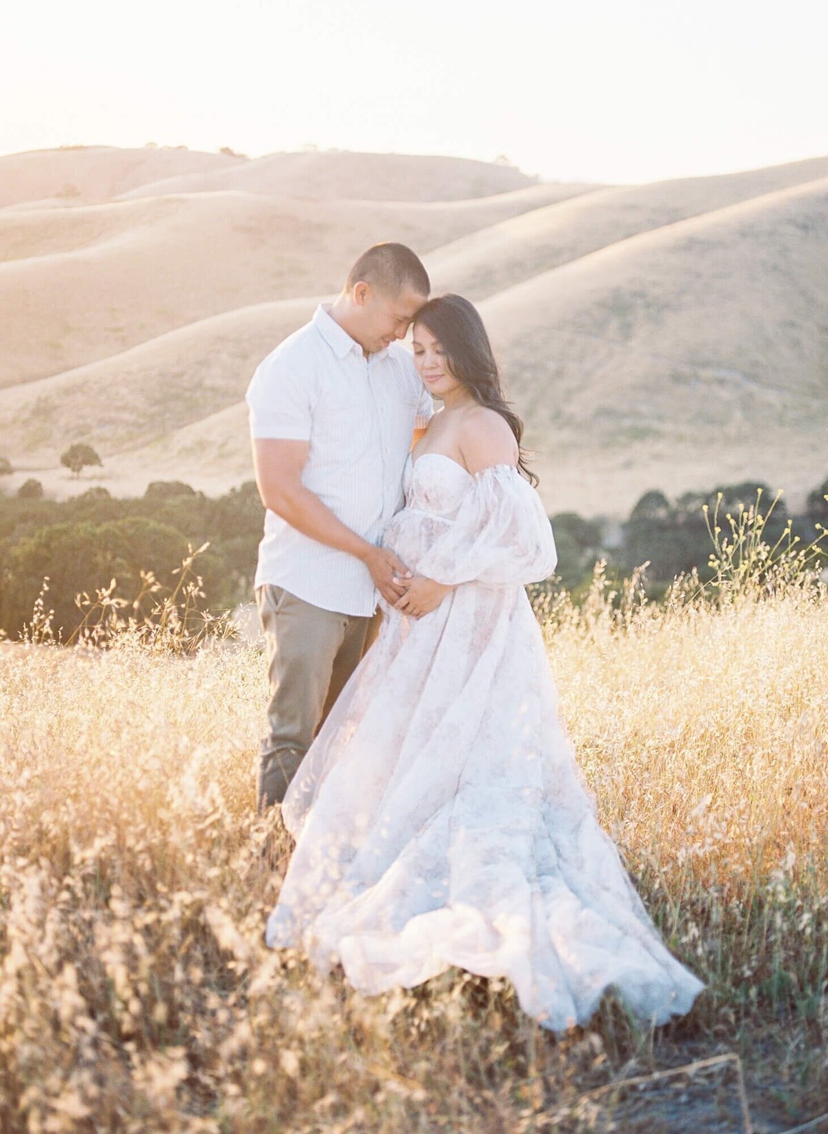 Pregnant woman and her husband framing her belly in a tulle dress taken by one of the top San Francisco Maternity Photographers Laurel Smith.