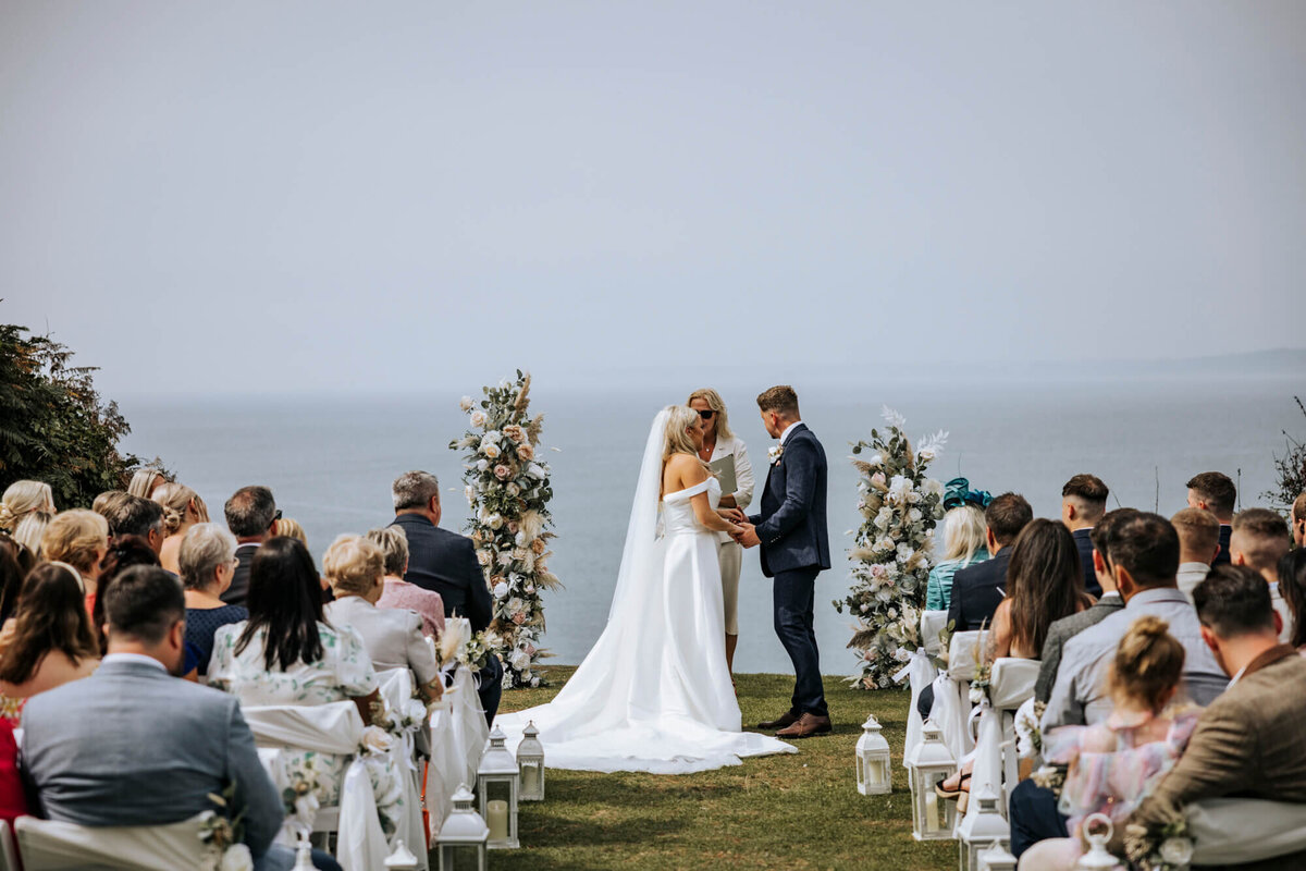 A couple getting married at their wedding ceremony with the sea in the background