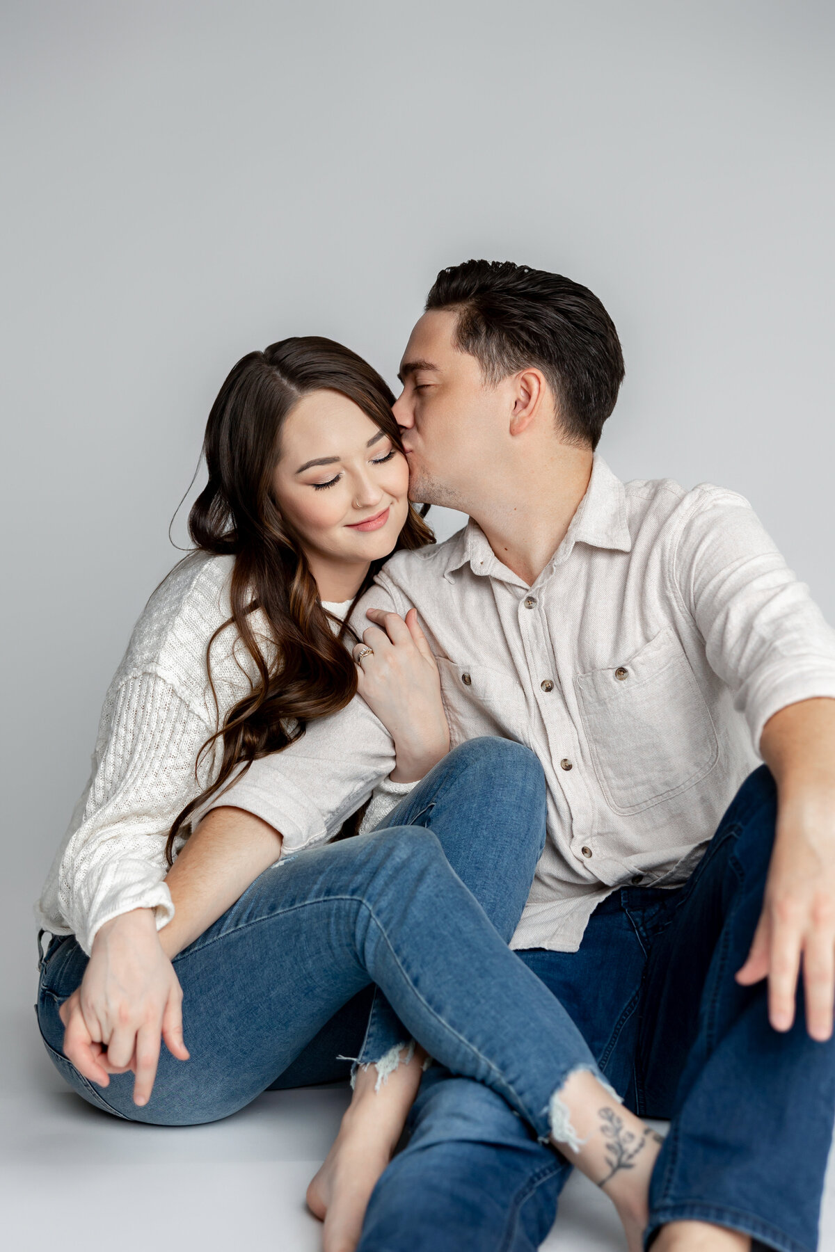 Couple sharing a tender moment, sitting close with natural smiles in studio. Photographed by Yucaipa family photographer Kaitlyn Dawn Photography.