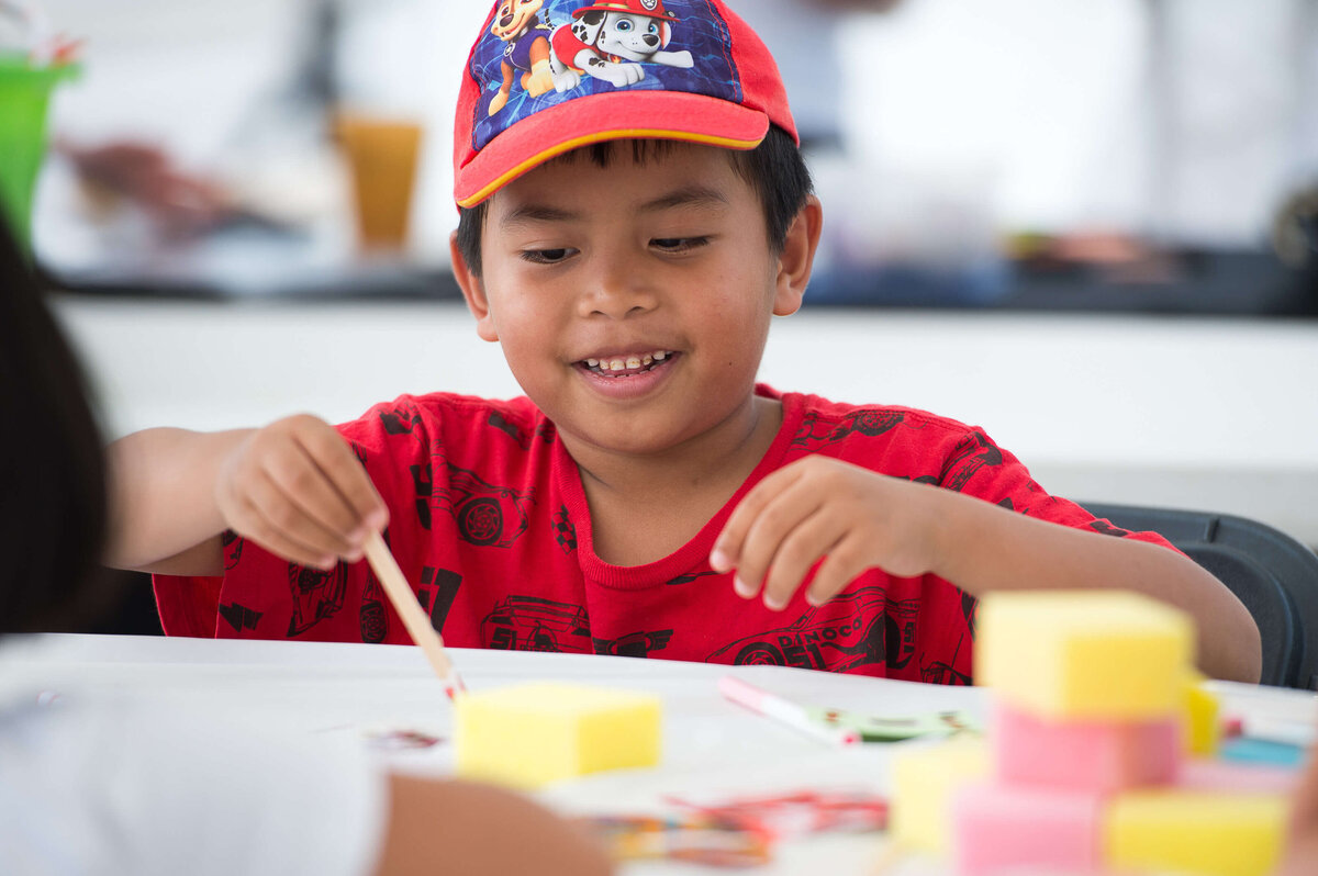 Ottawa event photos showing a boy in a red t-shirt painting as part of children's activities at a corporate event. Captured by JEMMAN Photography COMMERCIAL