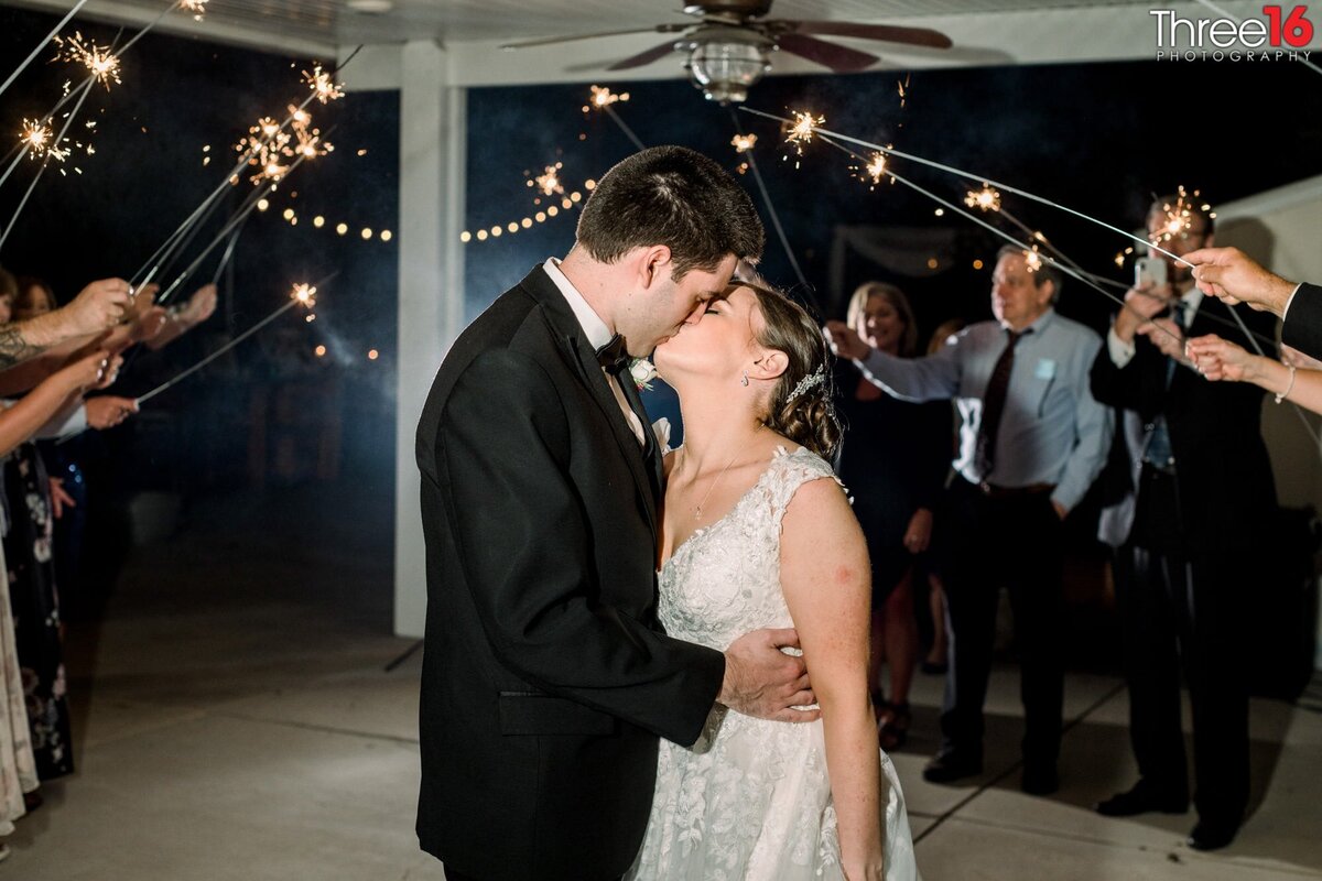 Bride and Groom share a kiss as the guests hold sparklers over their heads
