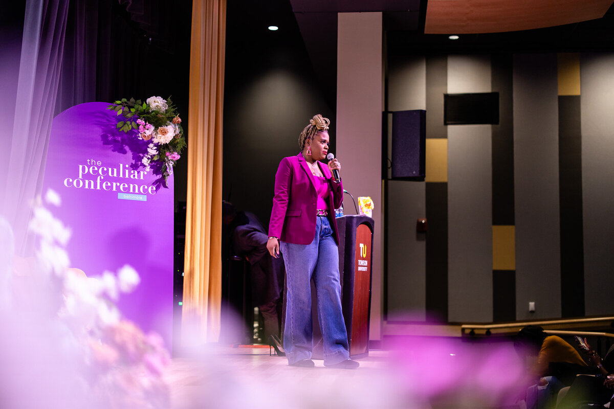 Lajune King speaking on stage at the Peculiar Conference 2023 as the Pink Starburst of Photography