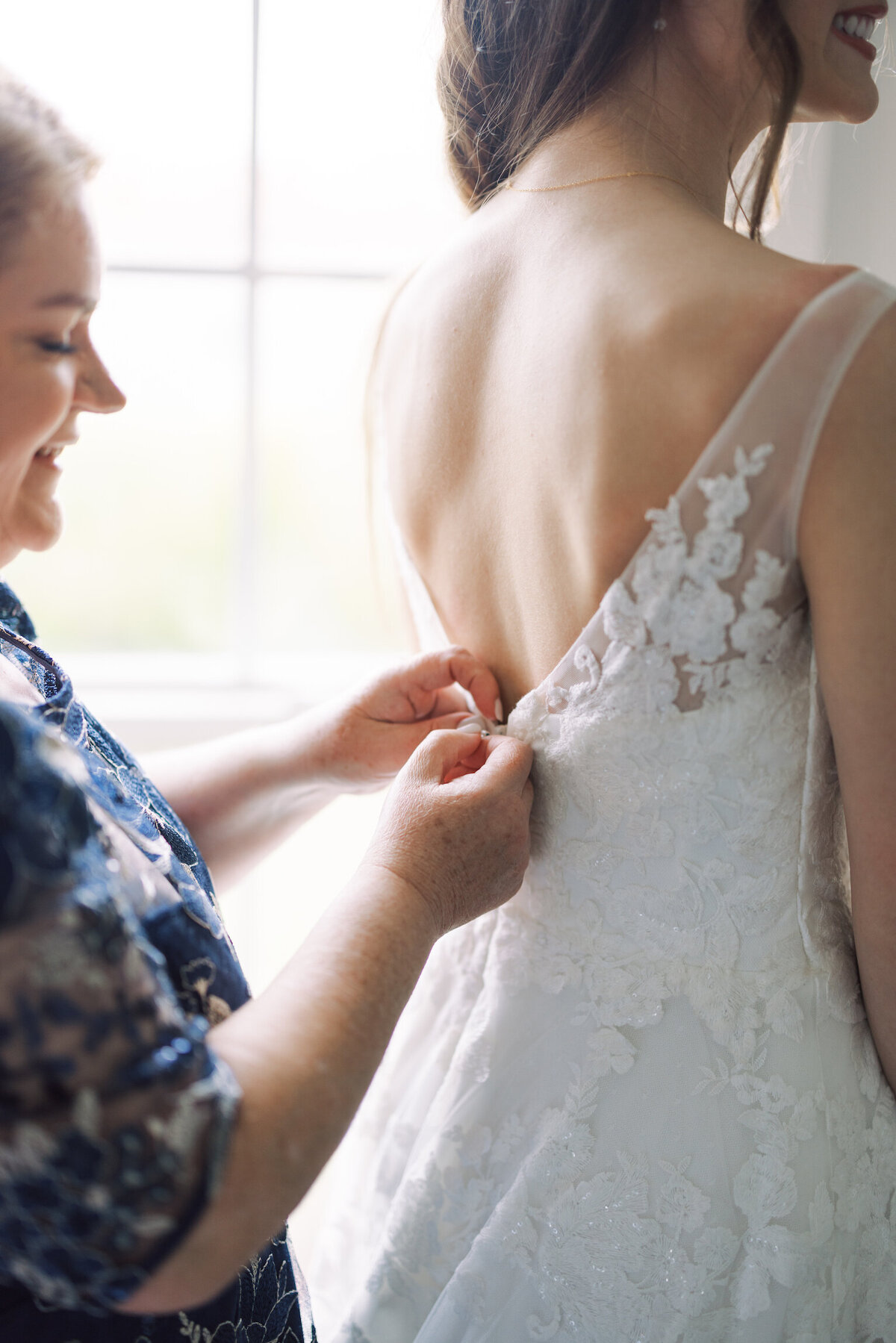 A heartfelt moment as the mother of the bride carefully buttons her daughter’s wedding dress, symbolizing love and family, beautifully captured on film by Morgan Alysse, Louisiana film photographer.