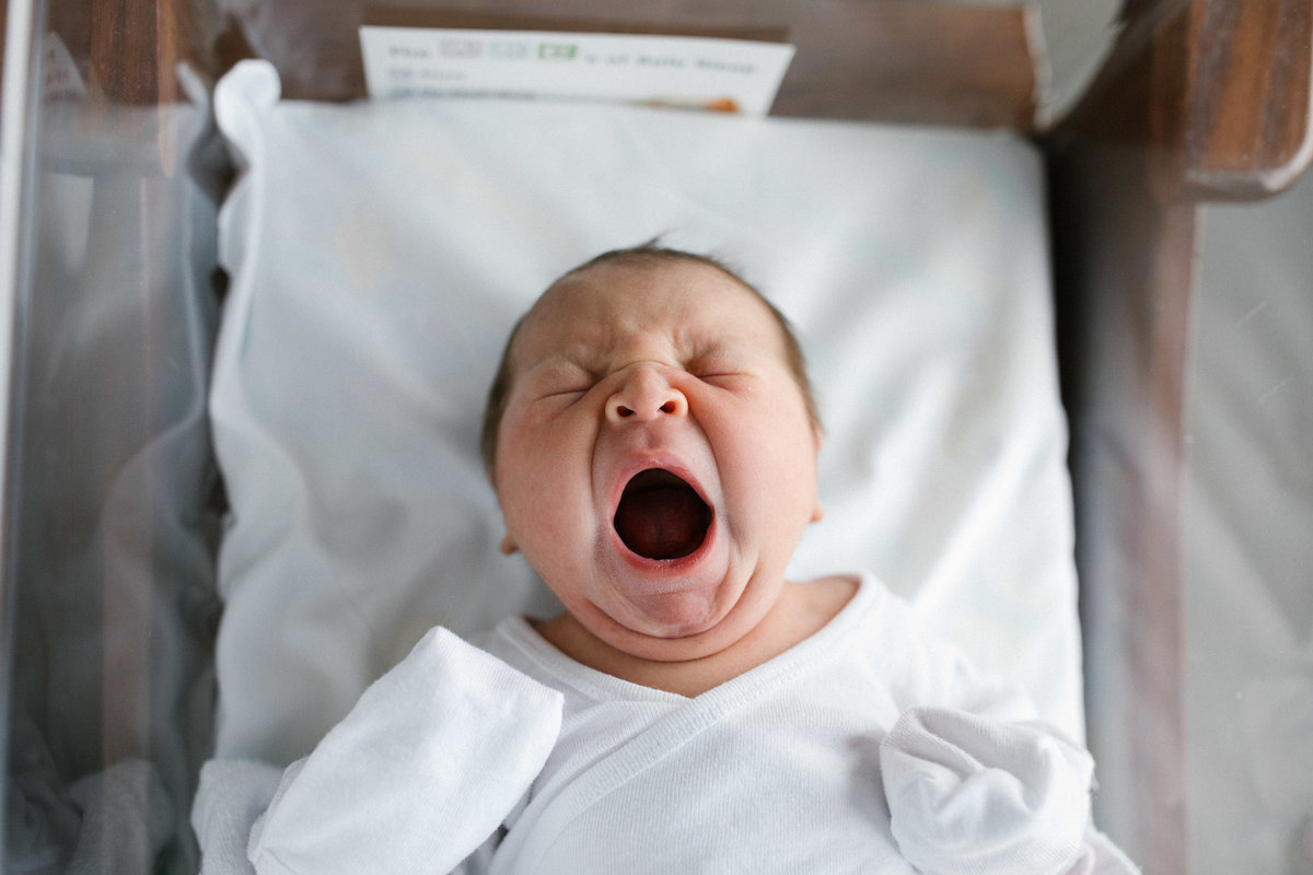 24 hour old baby yawning wearing a white onsie with Elle Baker Photography