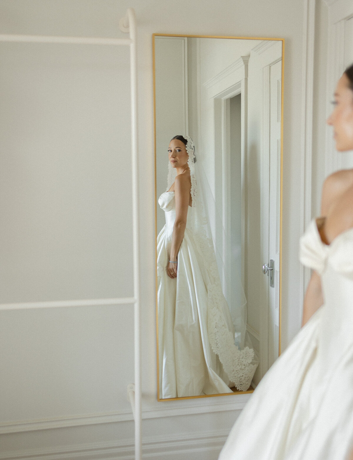Creative, poetic wedding photography shows a bride looking in a mirror just after getting ready