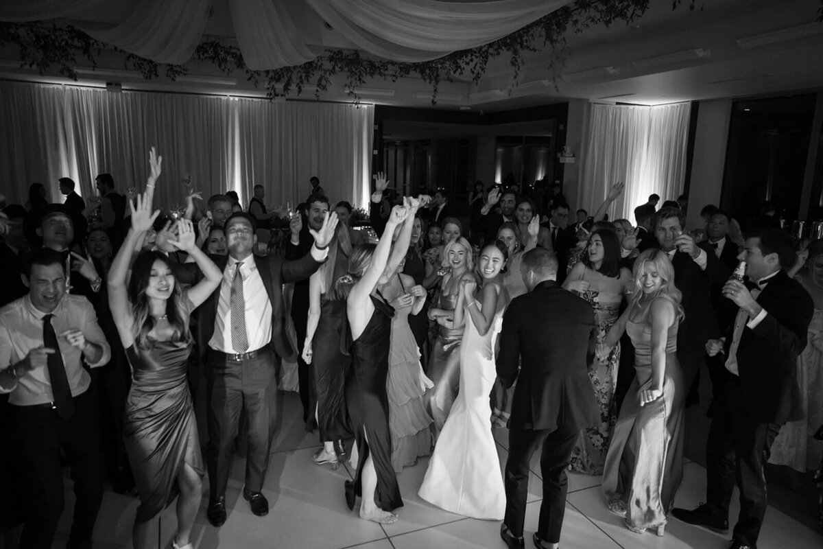 The bride and groom dance with a large group of guests at their Aspen Meadows Resort wedding reception.