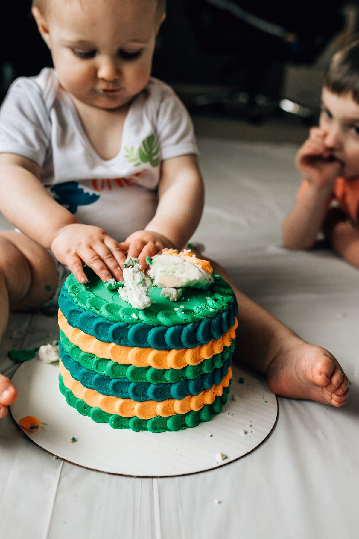 Baby sits on the floor with cake.