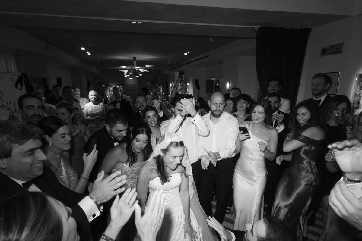 Bride dancing joyfully in center of crowded wedding dance floor

