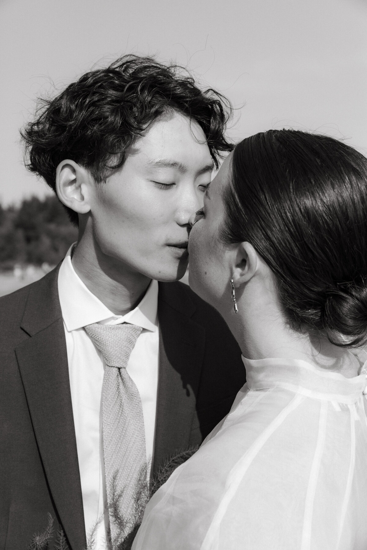 Soft black and white image of groom kissing bride on their wedding day.