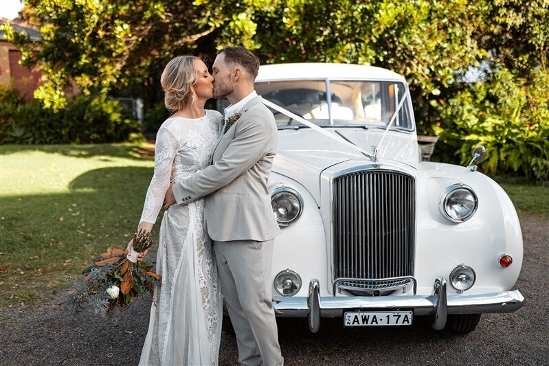 "Explore the enchanting world of Maddi & Jeremy's romantic kiss photoshoot captured against the backdrop of the bride's elegant car.