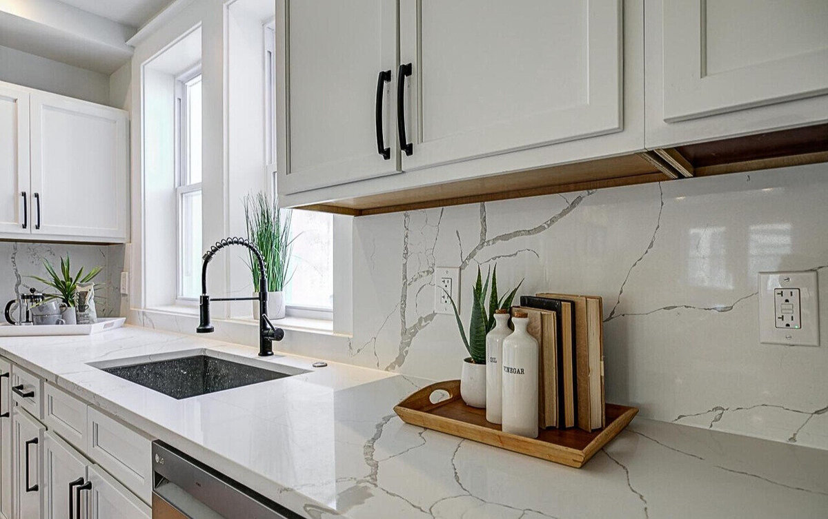 Modern kitchen design featuring white quartz countertops with waterfall edges, sleek black hardware, and custom cabinetry—highlighting precision craftsmanship and stylish finishes.