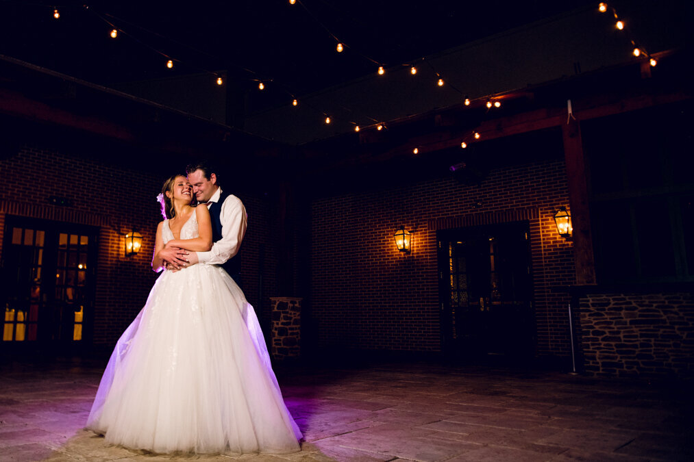 A bride and groom share their first dance at night.