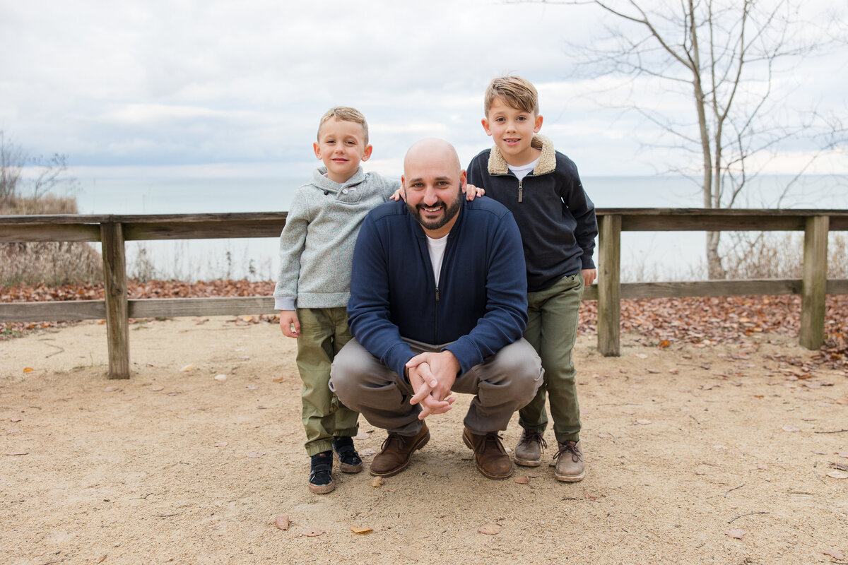 A dad with his two boys crouching down and smiling