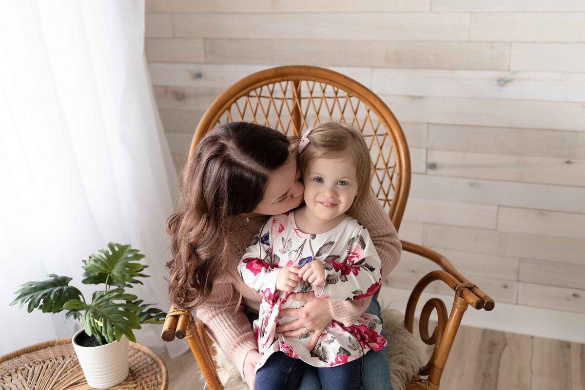 Mother Kissing Daughter In Boho Chair