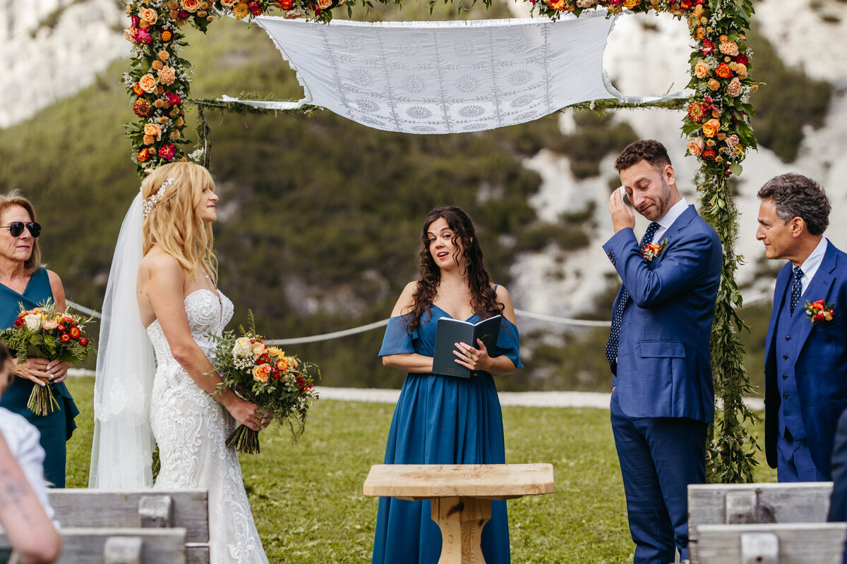 Outdoor Dolomites wedding ceremony with floral arch and mountain views