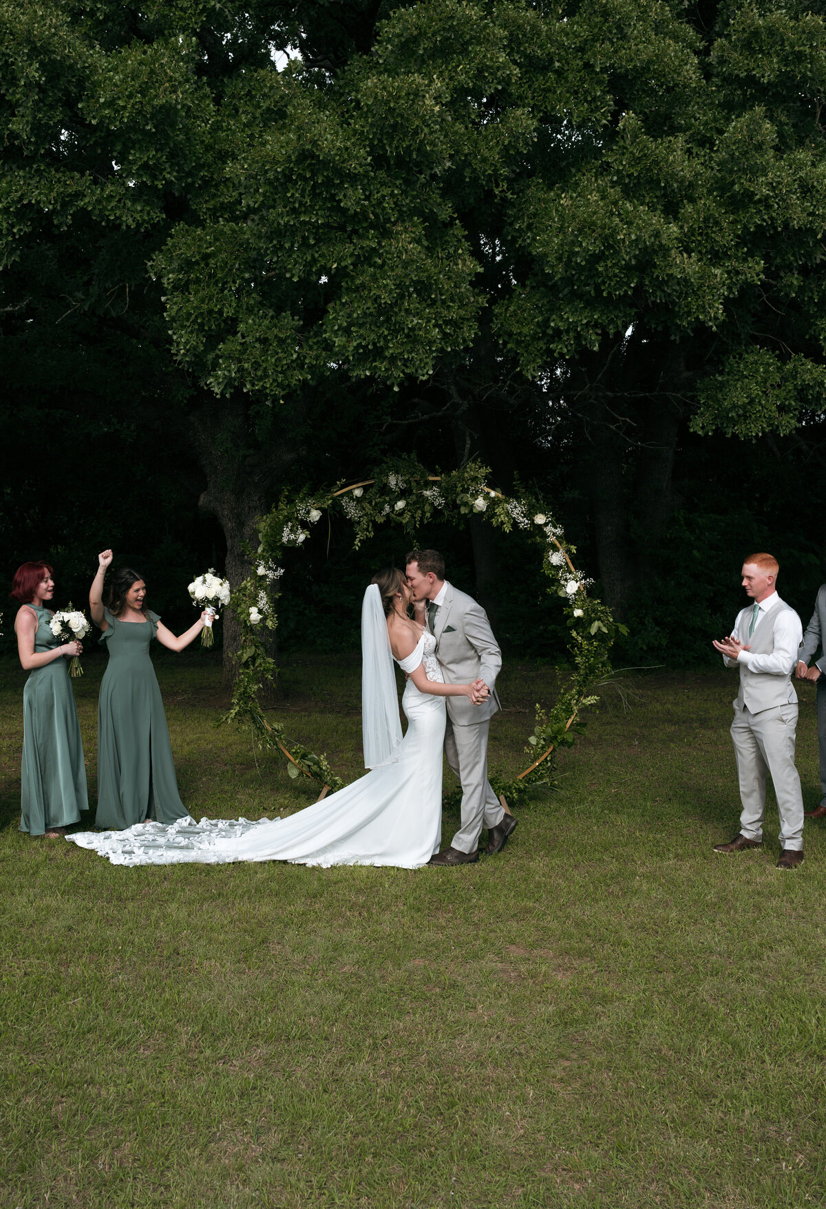 bride and groom sharing their first kiss as husband and wife at the alter while their friends and family cheer beside them