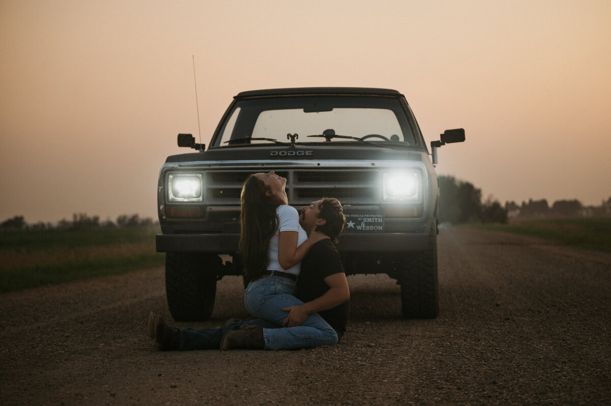 Couple sitting in front of truck on an old dirt road in Alberta