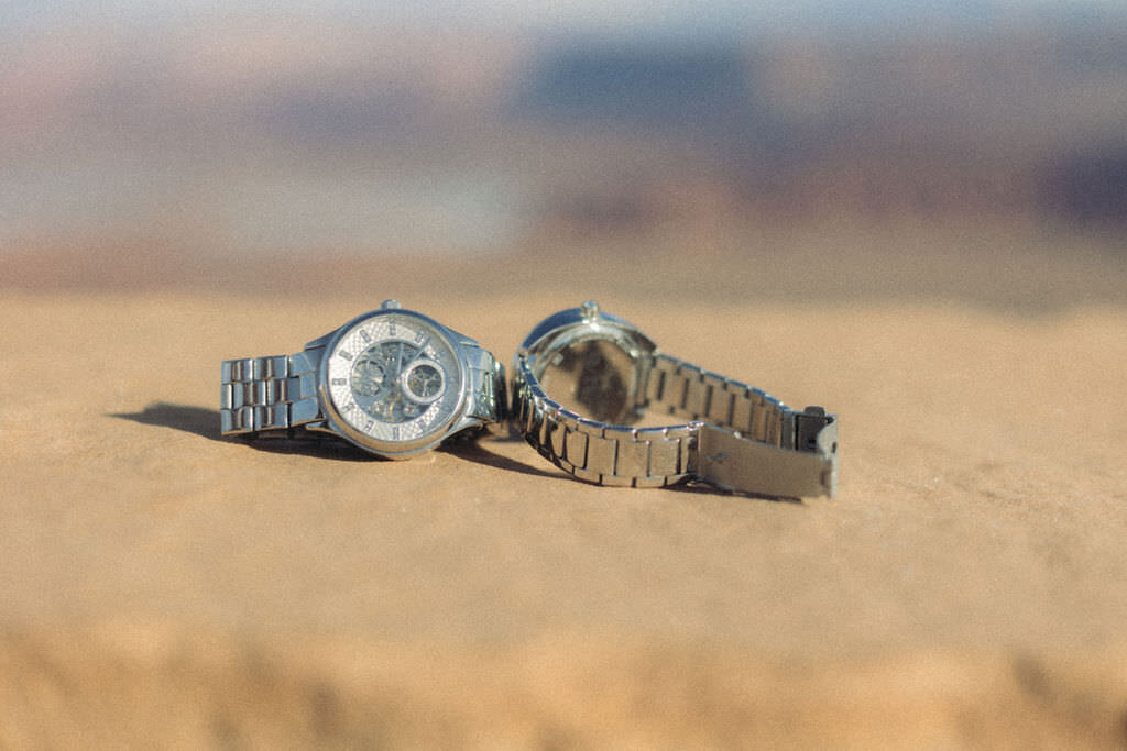 Two watches sitting on a rock.