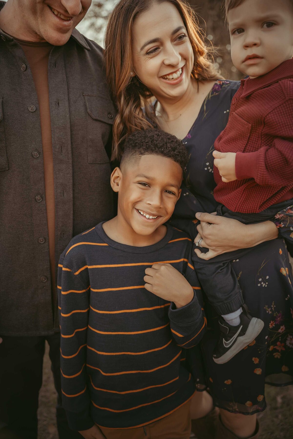 Mother and father with two sons. The mother is holding the younger son and looking at him while she smiles.