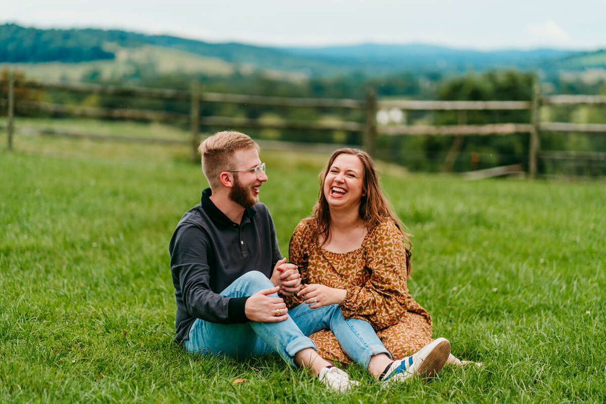 Couple cuddling in a field with rolling hills behind them