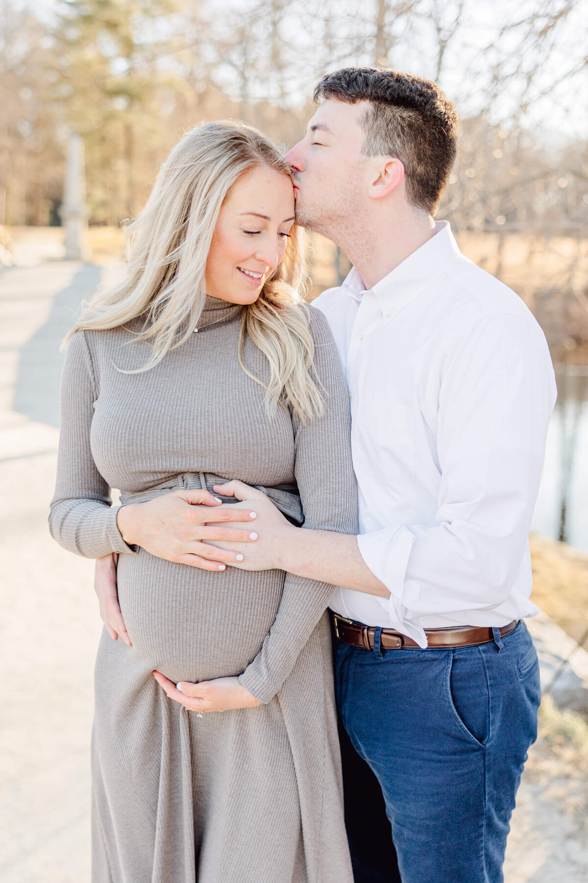 A man hugs his pregnant wife and kisses her on the temple