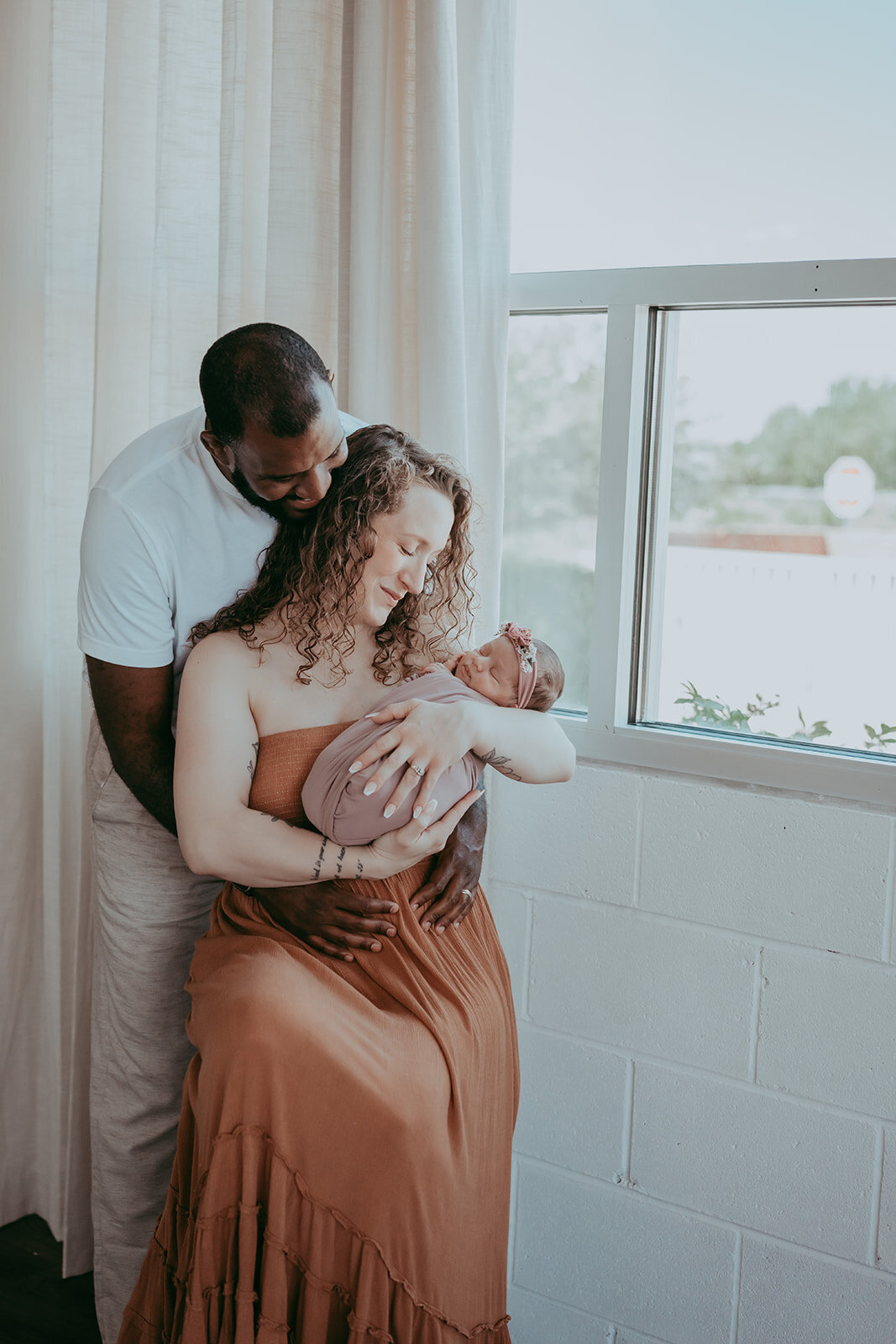 mom and dad admire their newborn baby during a studio session in parker colorado