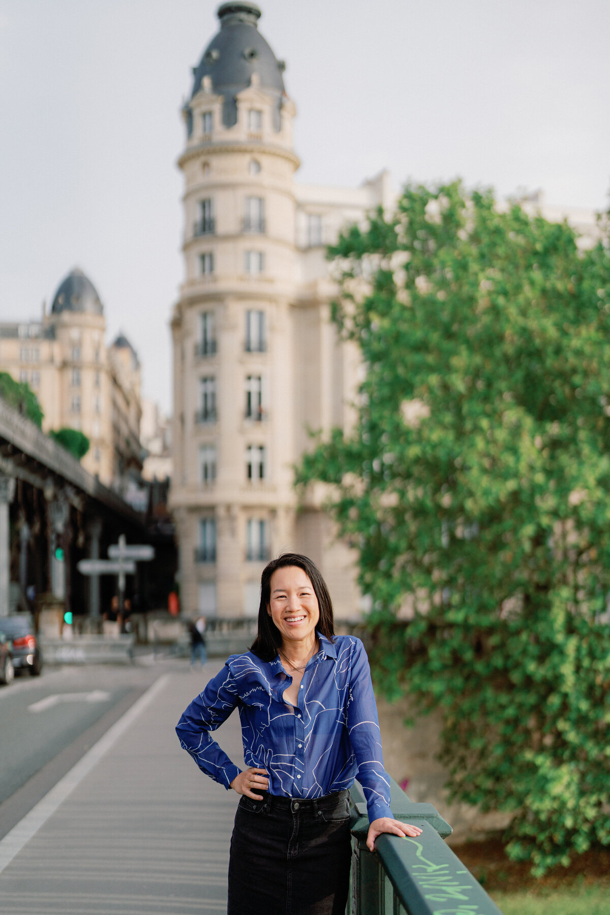 Woman in a blue top and a denim skirt smiles at the camer