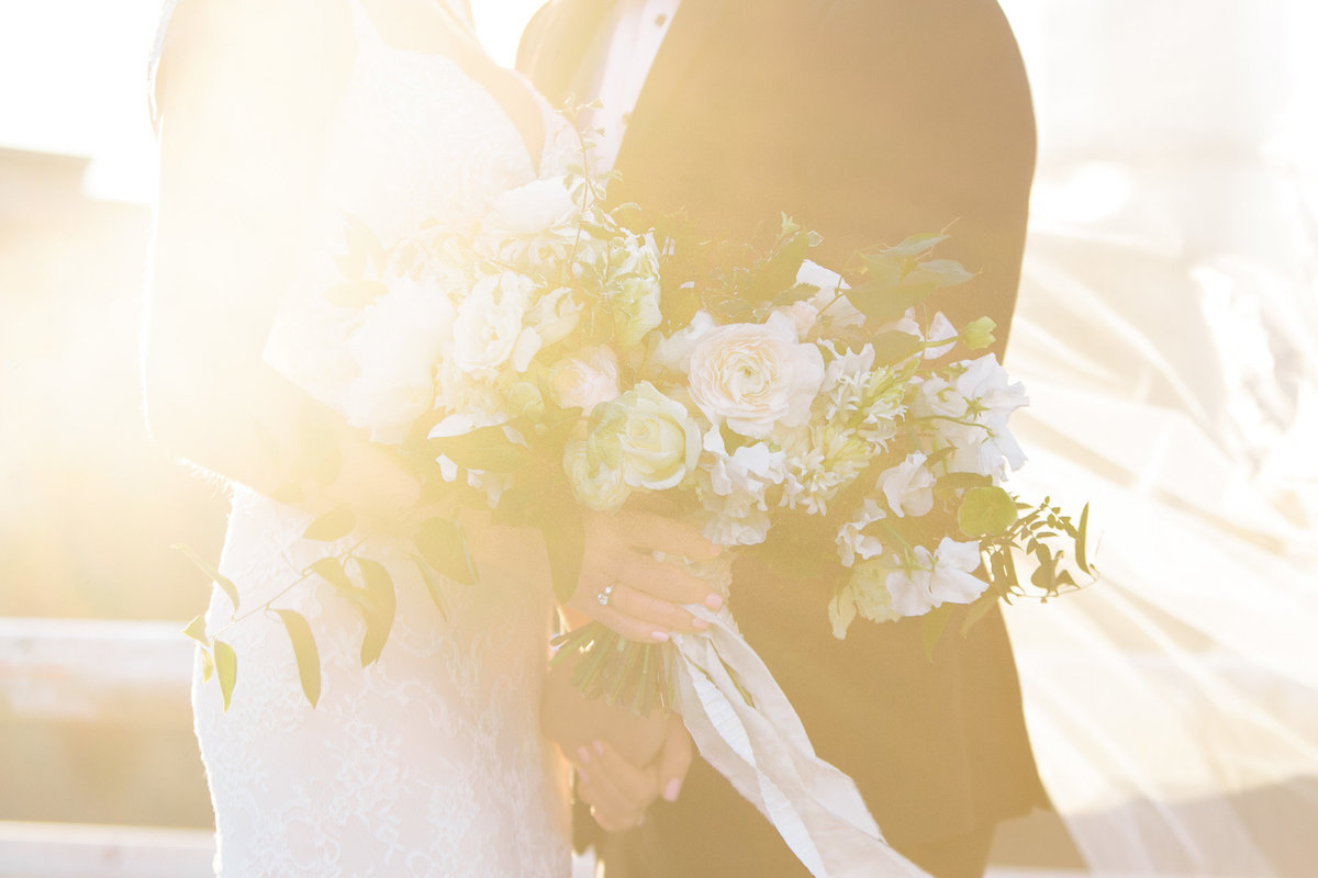 A bride and groom's embrace wrapped in golden sunlight.  Florals by Amy Osaba, photograph by Rebecca Cerasani.