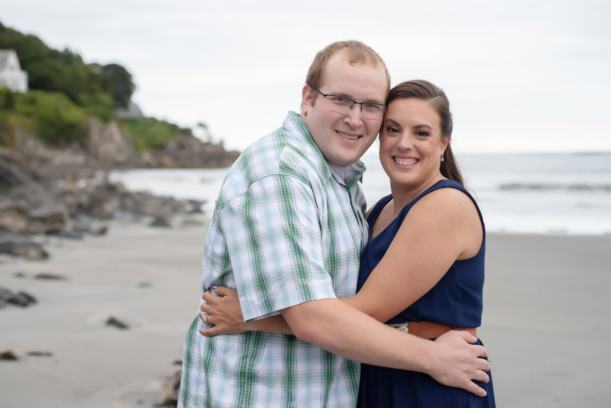 engaged couple hugging and smiling on York Harbor Beach Maine