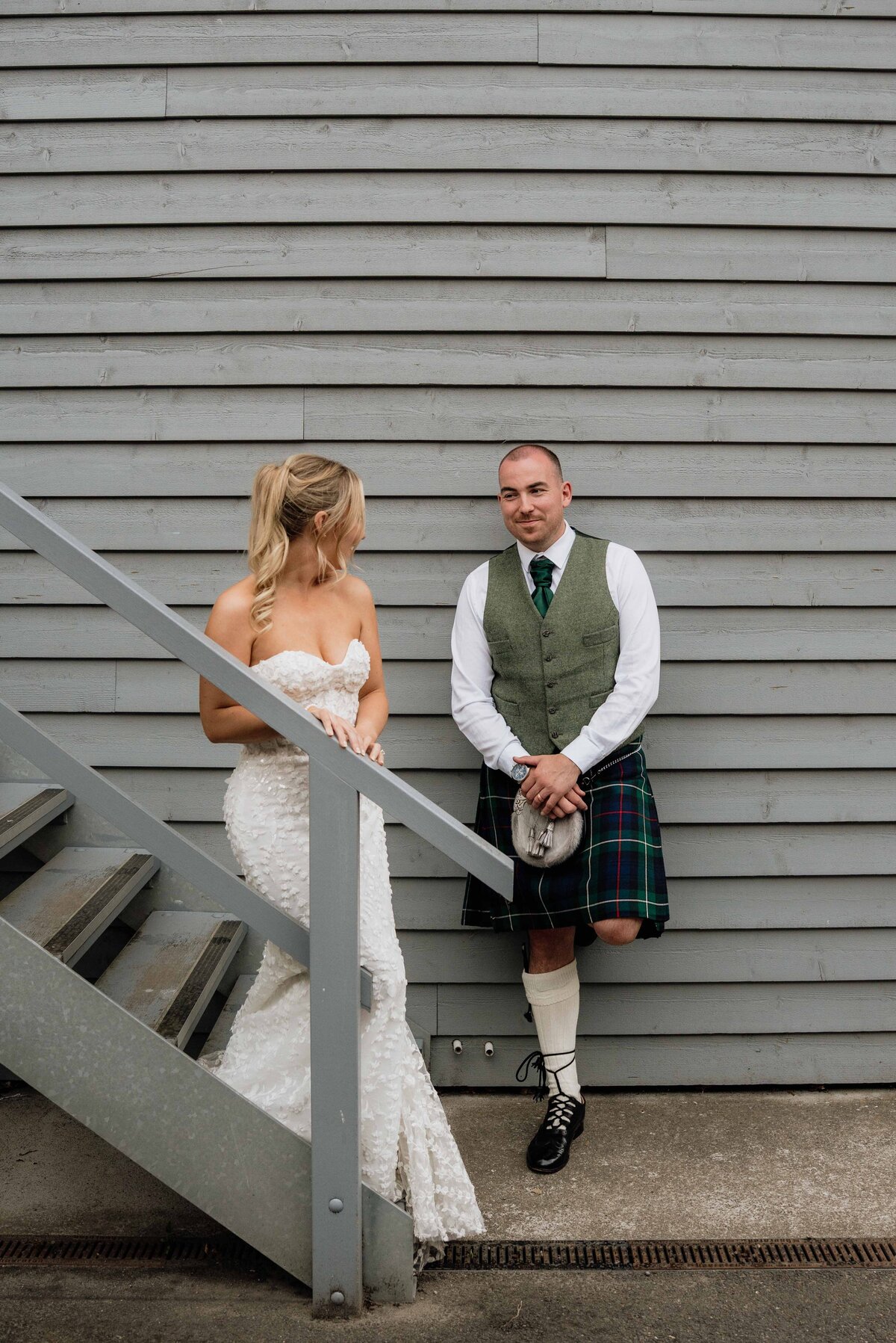 A bride ang groom pose candidly on an outdoors staircase at Barra Castle in Aberdeen.