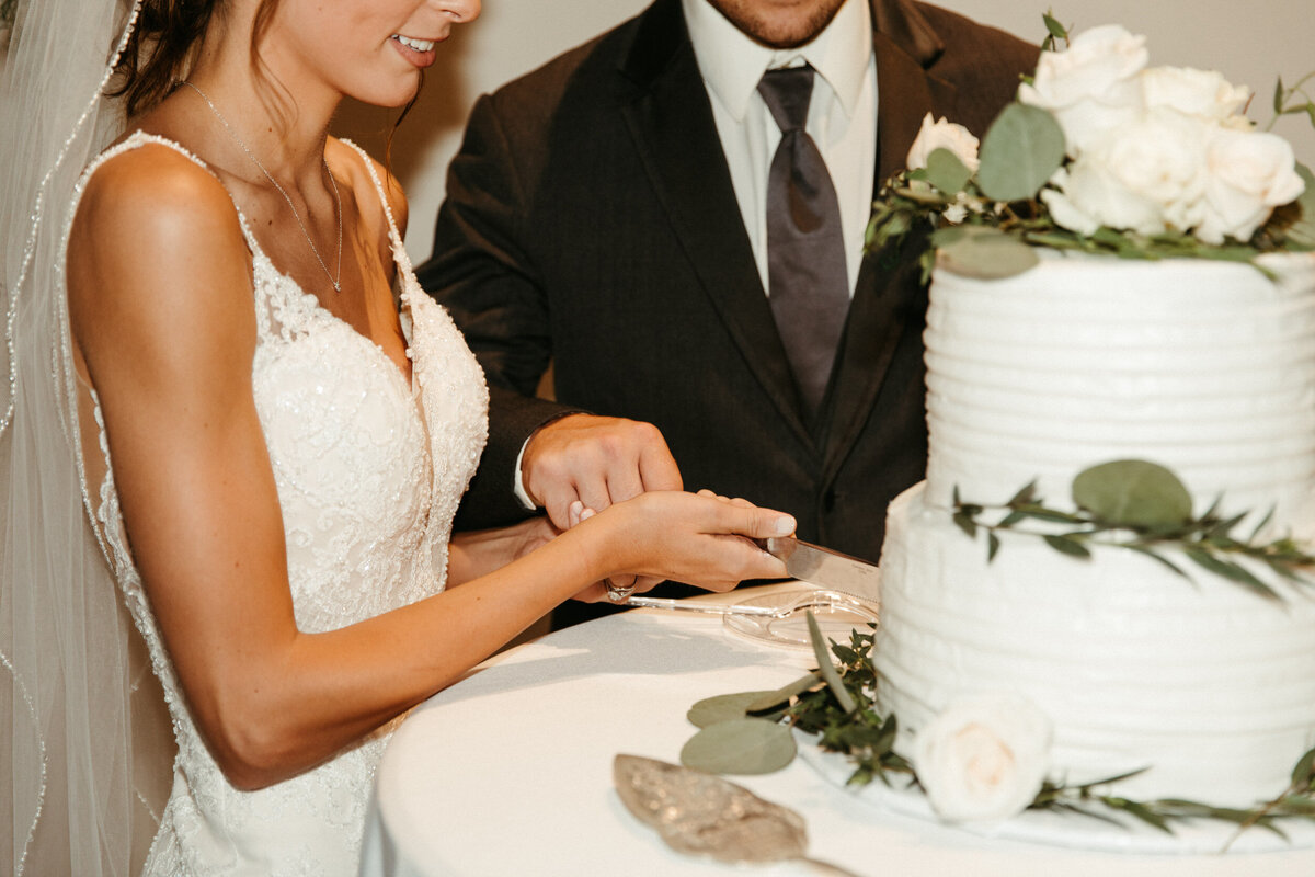 Bride and groom cutting their simple two tier wedding cake at their reception