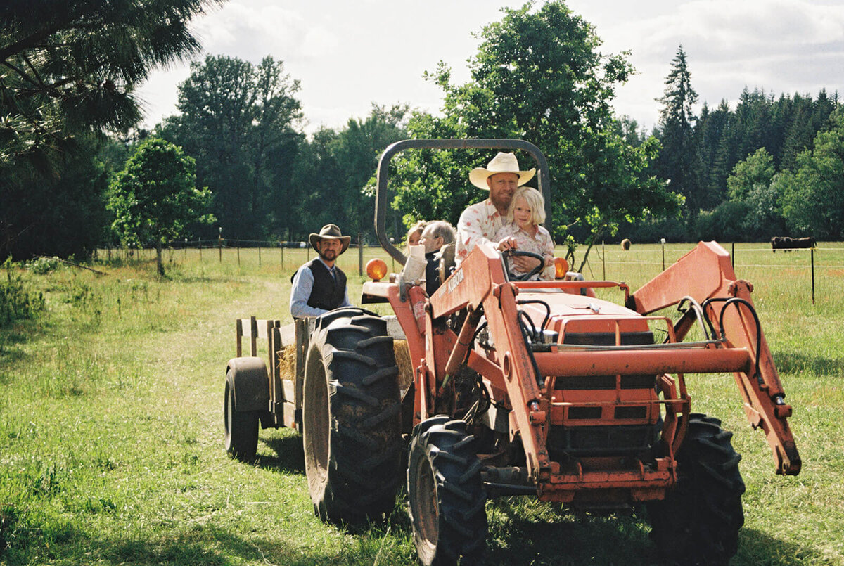 People riding on a tractor at an outdoor Veneta farm wedding.