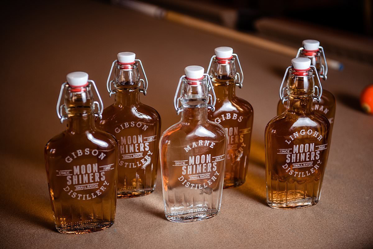 Custom engraved glass flasks that are gifts for the groomsmen filled with liquor