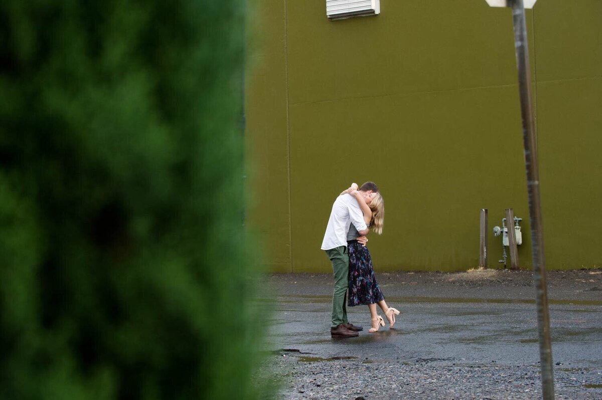 a couple embrace in front of a chartreuse green wall in nw portland