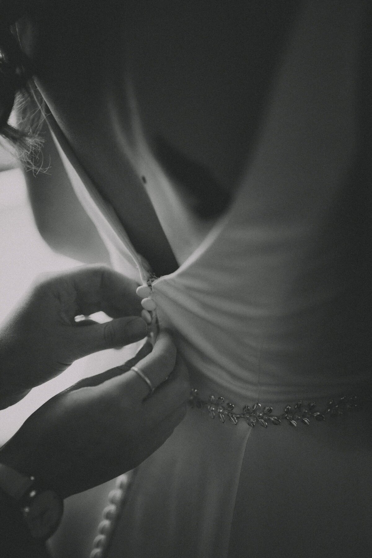 Bridesmaid does up buttons for a bride