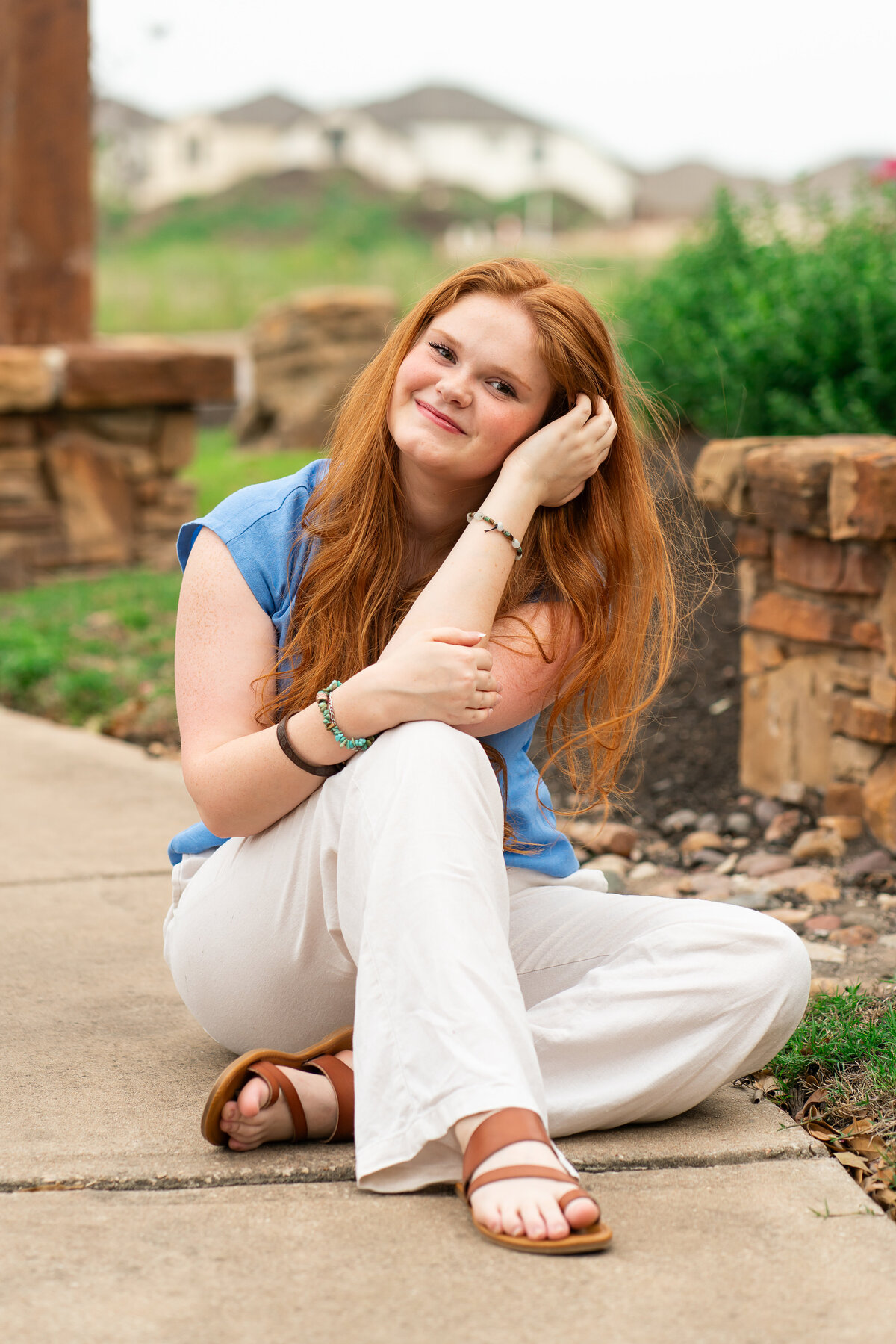 Red head high school senior girl posing in flowers for graduation photos. Austin Senior Graduation.