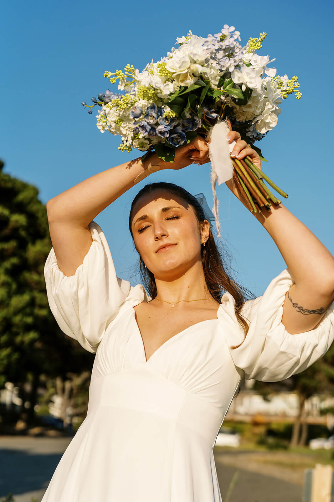 A woman holding a bouquet above her head with her eyes closed.