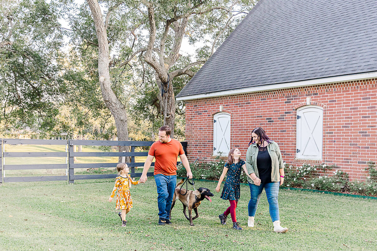 Family and their dog walking by their barn