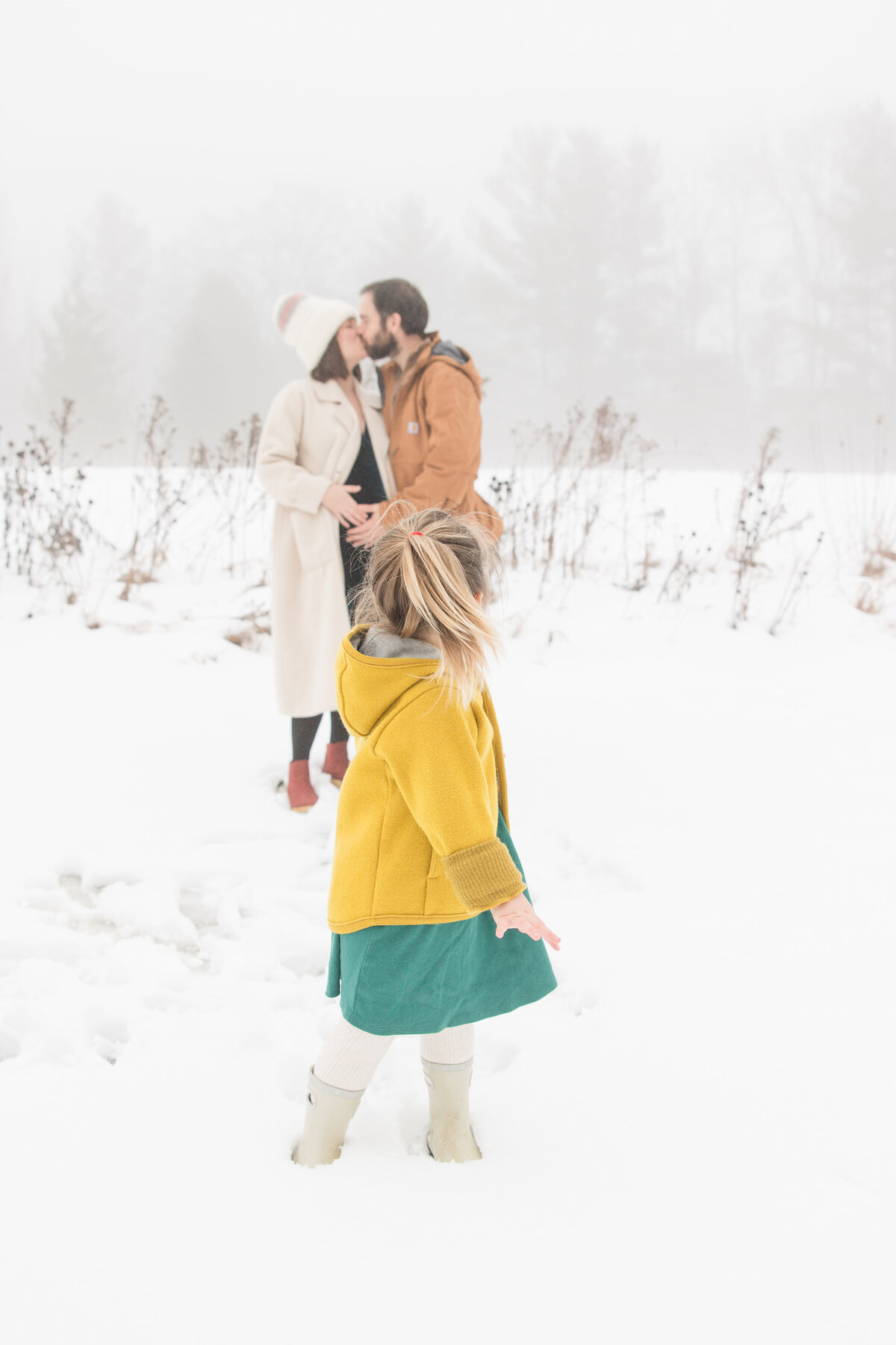 A little girl looking back at her parents who are sharing a kiss