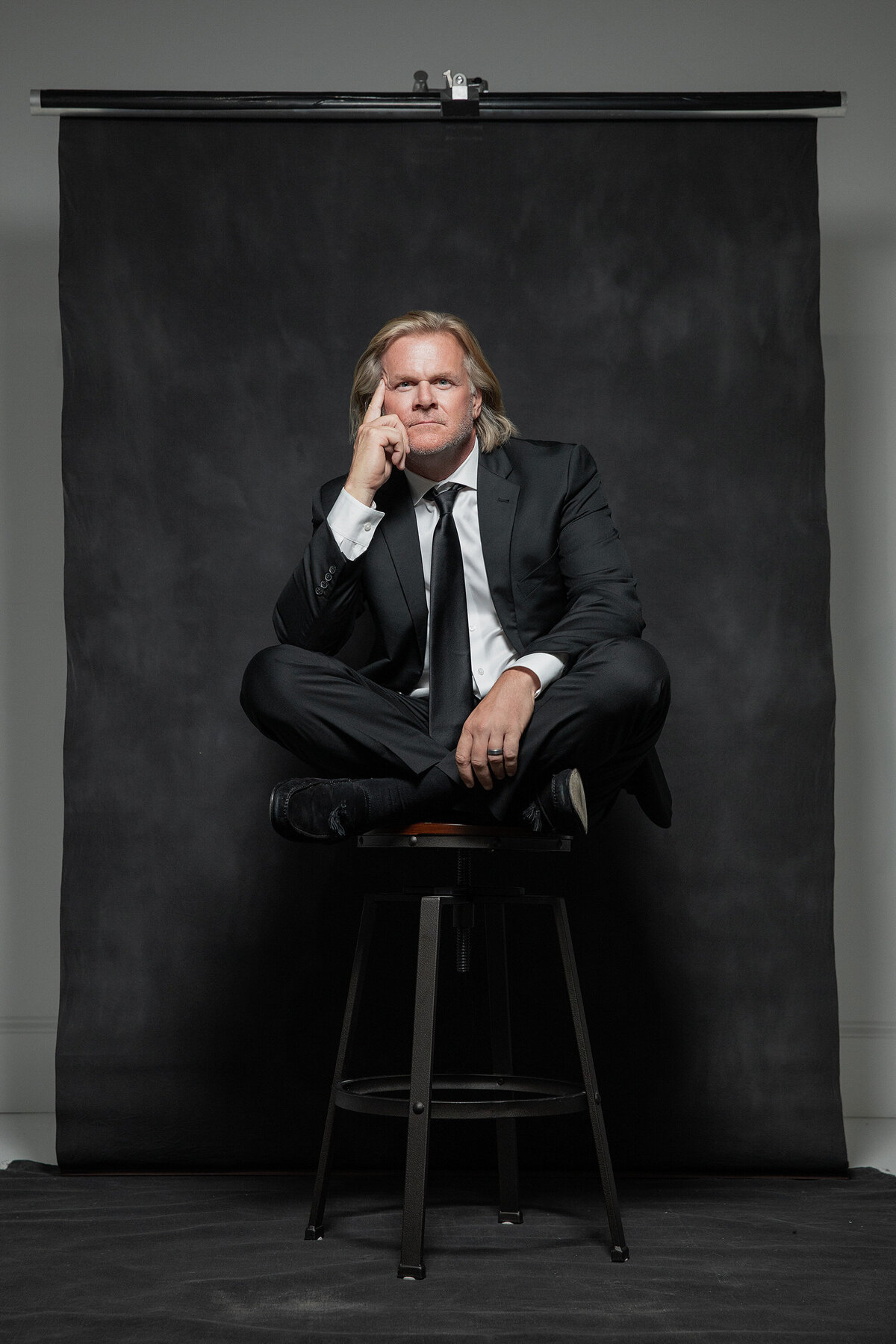 A man sitting crossed legged on a stool