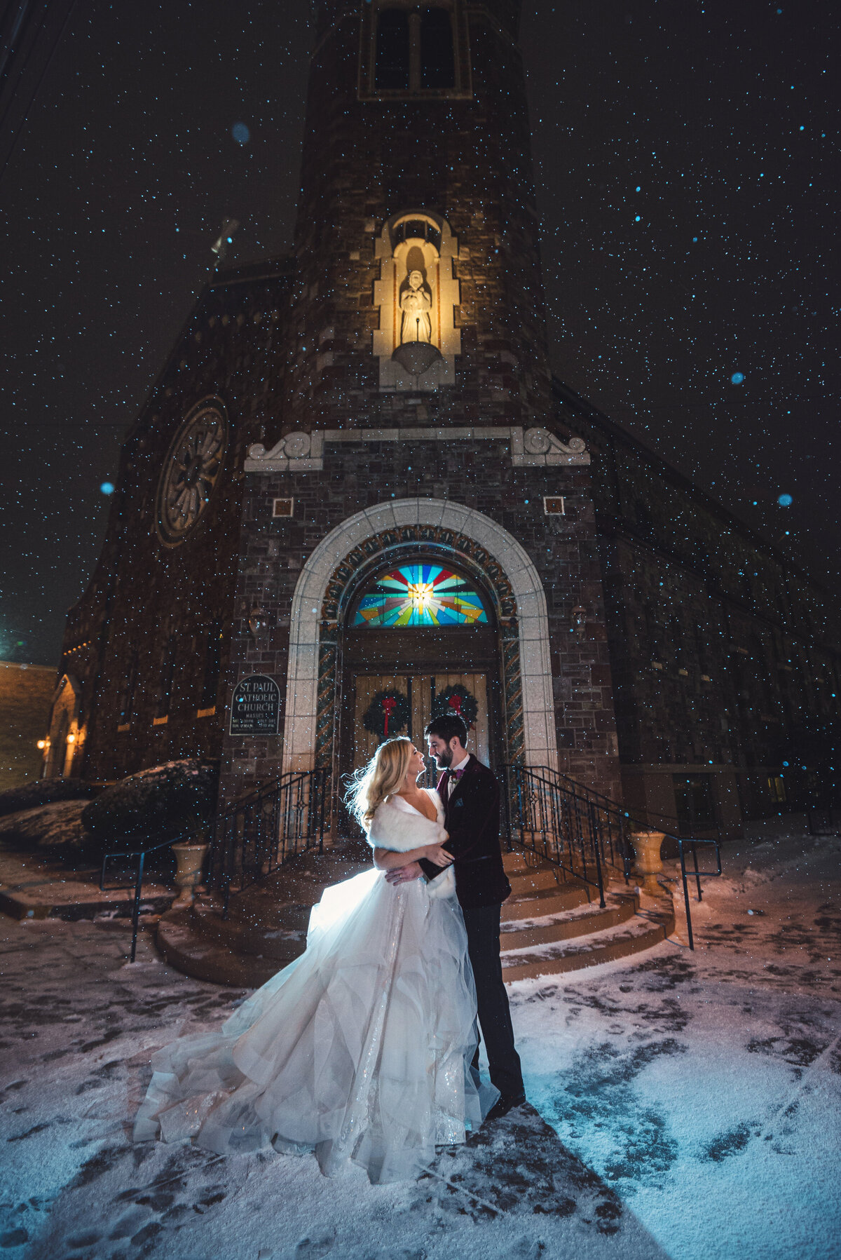 Wedding couple kissing in the snow at night.
