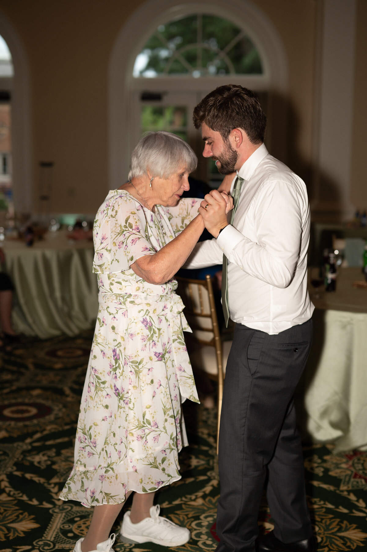 A person dancing with their elderly family member at their wedding reception