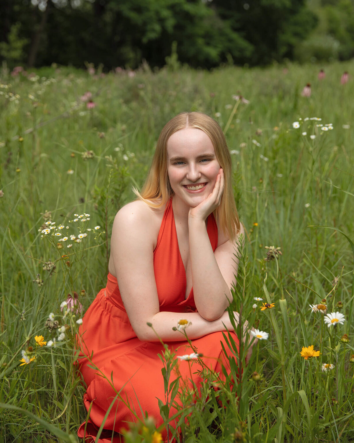 Senior girl in a peach dress posing in a field of wild flowers.