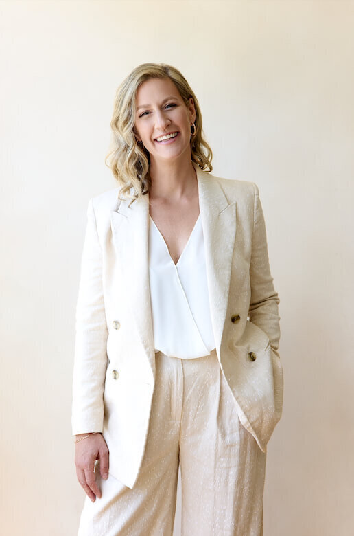 Business Headshot of a woman wearing a boho suit on a beige background smiling at the camera