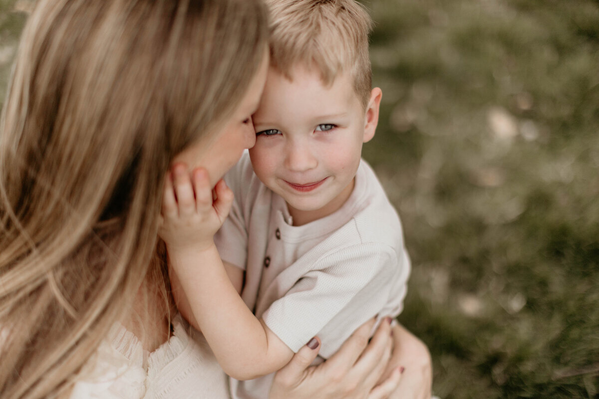 Son putting his hand on mom's cheek while mom looks at her son. 