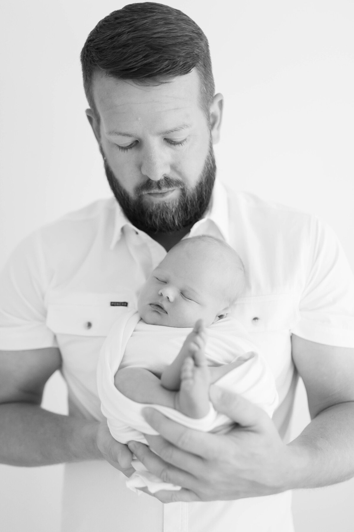 IMAGE OF DAD HOLDING NEWBORN BABY IN PHOTOGRAPHY STUDIO IN GLASGOW KENTUCKY BY MORGAN WORLEY PHOTOGRAPHY
