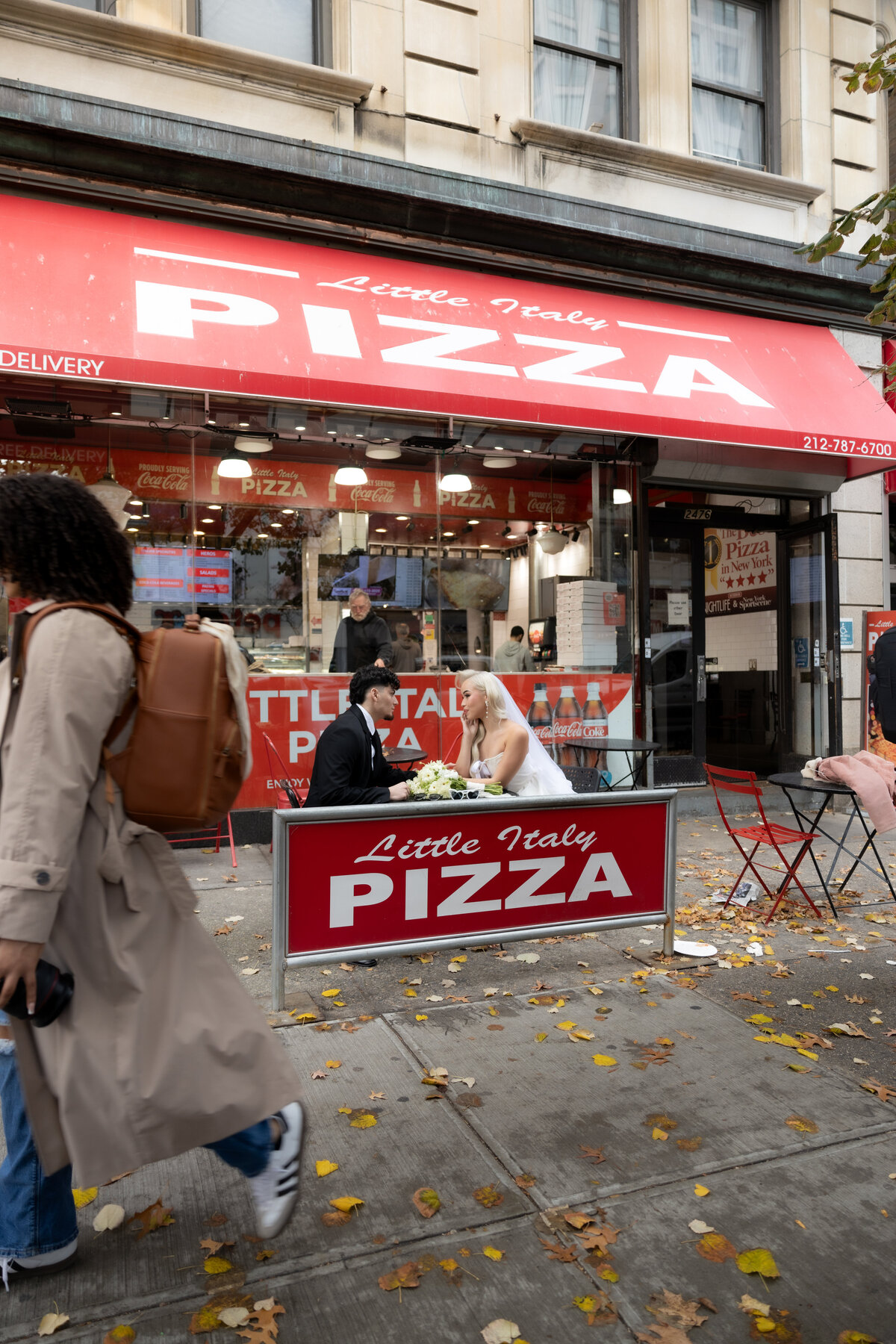A romantic photo of the couple sharing a pizza under the warm lights of a NYC pizza shop.