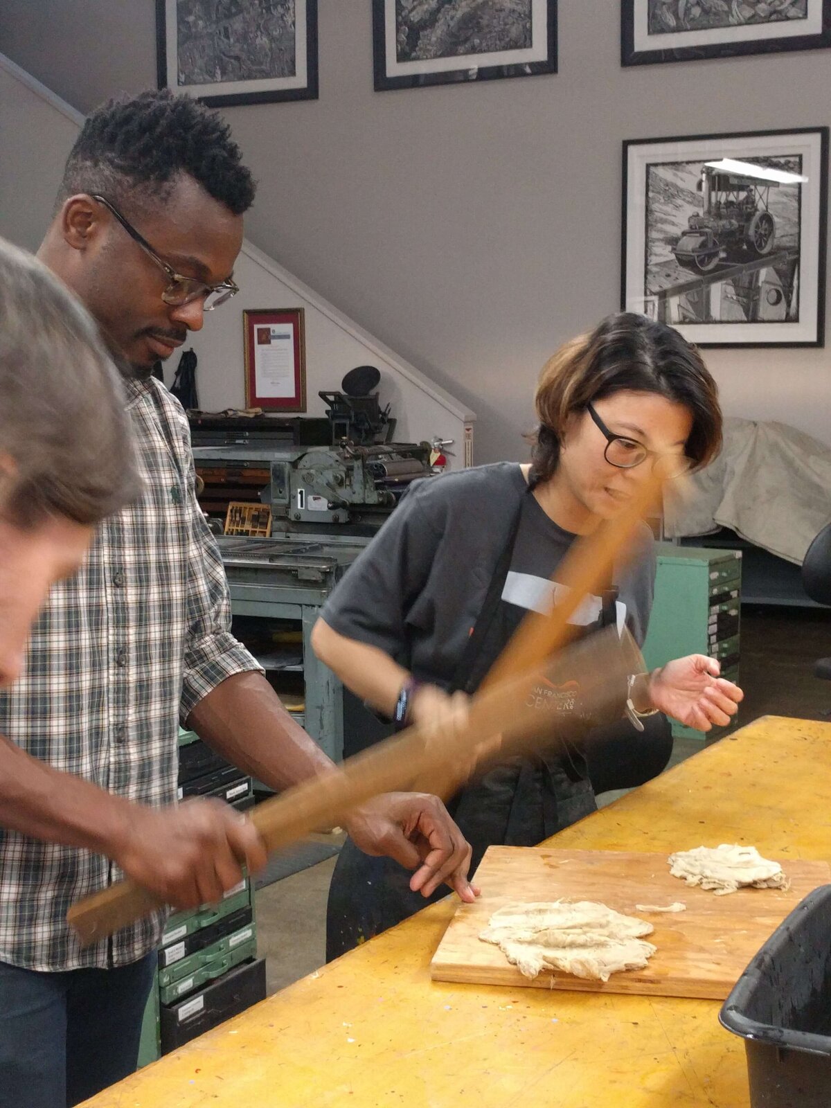 Workshop participants pounding kozo fiber with wooden mallets as part of traditional washi preparation.